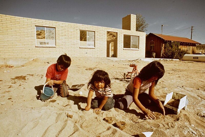 Дети навахо играют в песке за строящимся новым домом