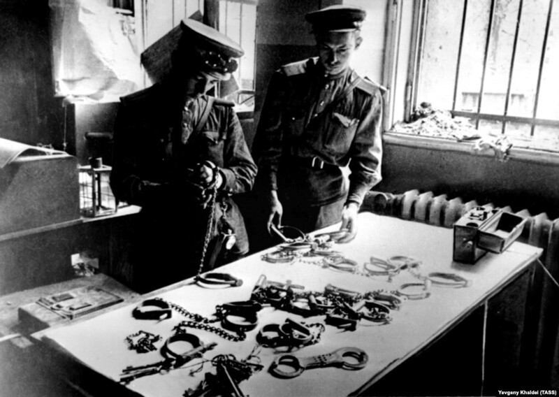 Советские солдаты рассматривают наручники, найденные в штаб-квартире Государственной тайной полиции (Гестапо) в Берлине