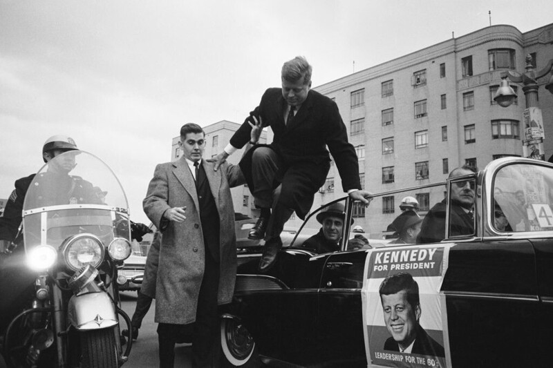 Кандидат в президенты Джон Ф. Кеннеди выпрыгивает из машины, 1960 году