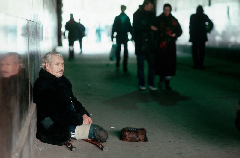  Бездомный инвалид сидит на холодном тротуаре