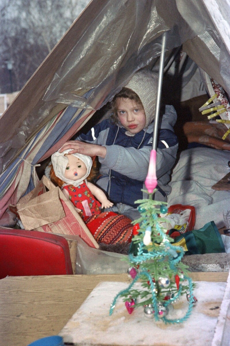 Маленькая девочка играет со своей куклой в палатке, где она живет со своей бездомной семьей недалеко от Красной площади, 16 декабря
