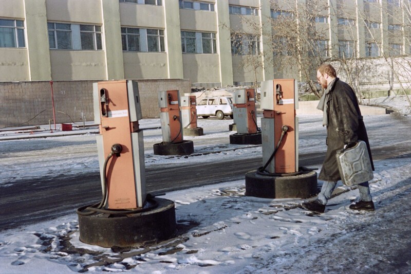 Мужчина с канистрами идет через закрытую заправку в Москве 27 декабря