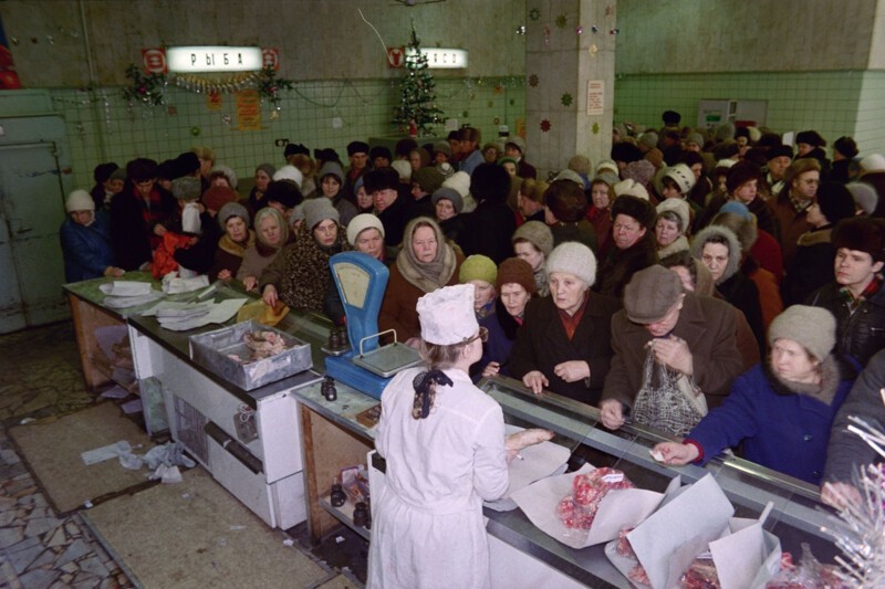 Москвичи выстраиваются в очередь у прилавка, чтобы купить еды к предстоящему празднованию Нового года. 29 декабря