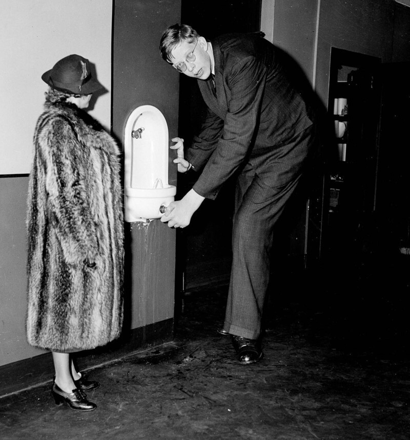Уодлоу наклоняется к питьевому фонтанчику во время визита в офис Daily News в Нью-Йорке. 1937 г.