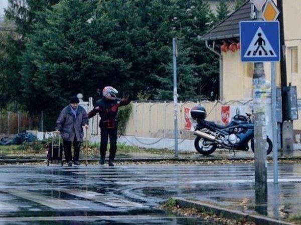 Мотоциклист остановил движение, чтобы помочь старушке перейти через дорогу