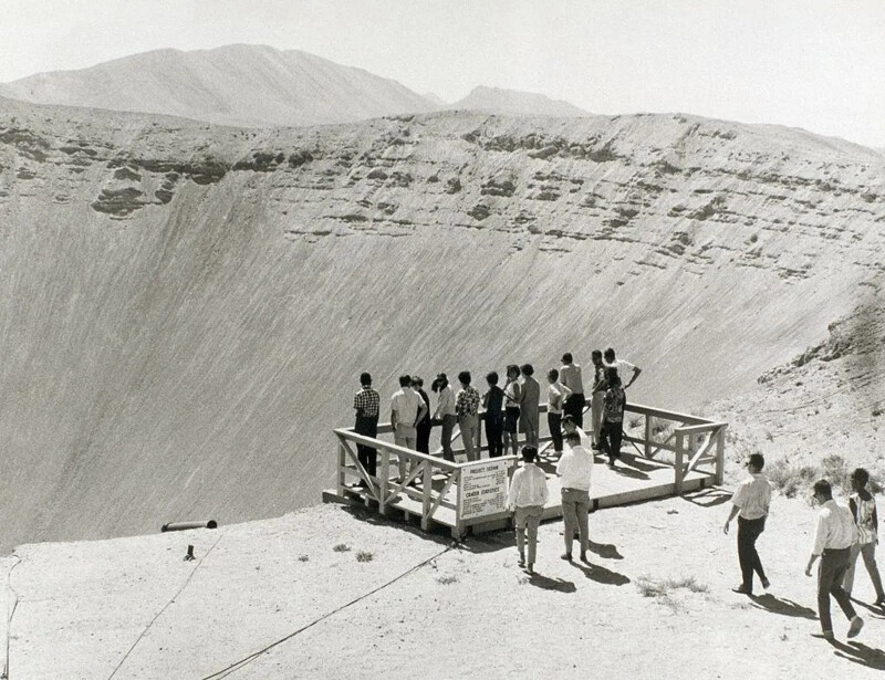Люди стоят на краю гигантского кратера, образовавшегося в результате ядерного испытательного взрыва проекта Седан, 1950-е годы