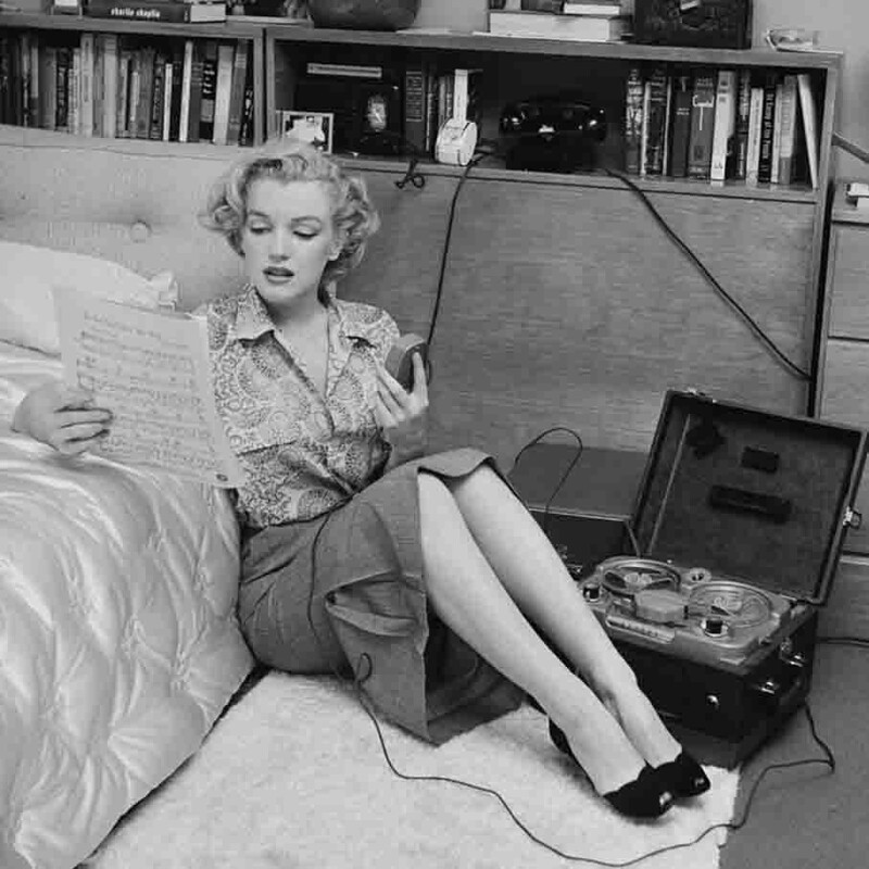  Мэрилин Монро у себя в спальне следит по нотам за исполнением музыкального произведения. Около 1950 года