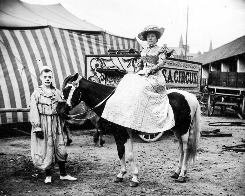 Дама позирует на лошади рядом с клоуном