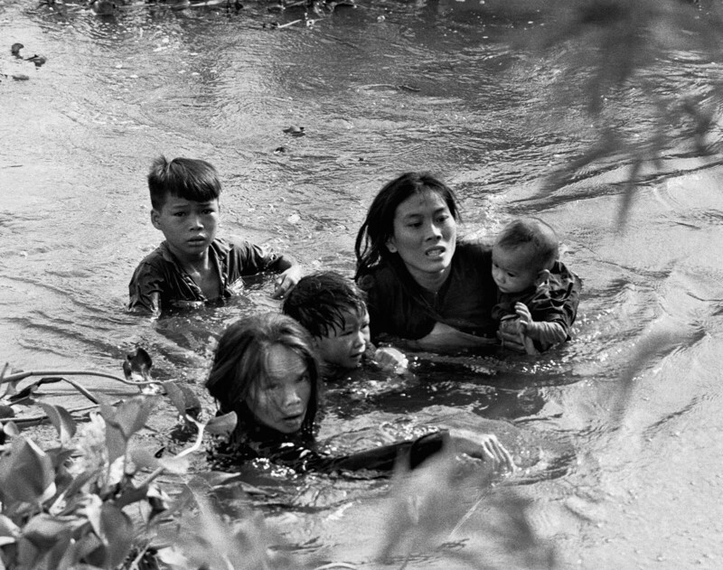 Женщина с детьми переплывают реку, пытаясь спастись от нападения морской пехоты США во время проведения военной операции «Пиранья» в Южном Вьетнаме. 1965 год.