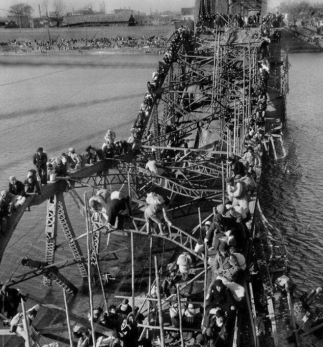 Корейские беженцы покидают Северную Корею, преодолевая искореженный в результате авиаудара мост, 1950 год