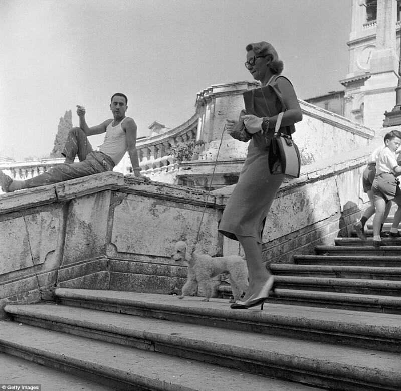 Отпуск в Риме: итальянский рабочий смотрит на американскую туристку, которая выгуливает пуделя на Испанской лестнице в Риме, около 1955 года.