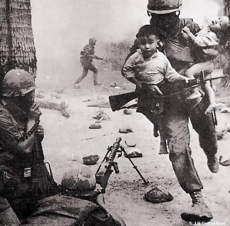 Морской пехотинец США спасает двух вьетнамских детей во время перестрелки в городе Хюэ. 1968 год. Вьетнам..