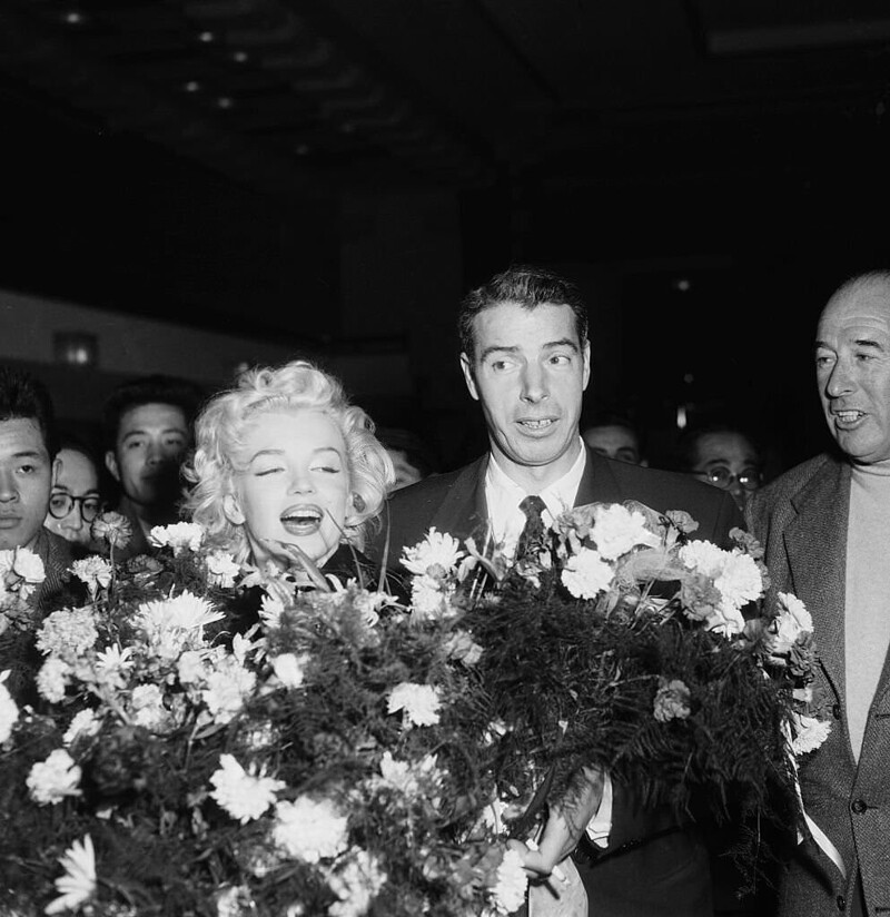 18. Мэрилин Монро и Джо Ди Маджо получают букеты цветов по прибытии в Токио, где знаменитая пара проведёт свой медовый месяц