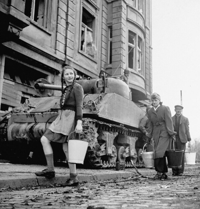 Немецкая семья несёт воду мимо танка "Шерман". Кельн, Германия, 1945 год