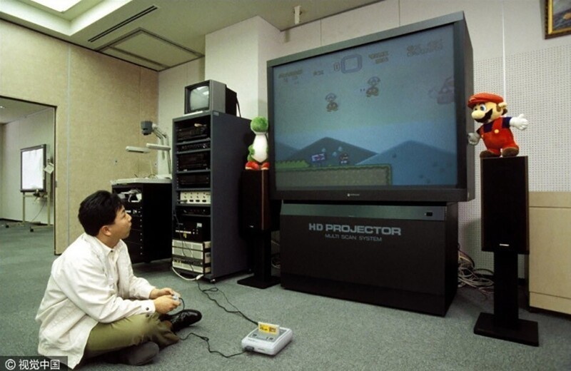 Сотрудник команды разработки Super Mario для SNES играет на большом проекционном телевизоре Hitachi, апрель 1992 год
