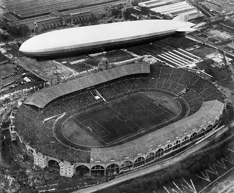 Немецкий аэростат Graf Zeppelin, наполненный водородом, медленно перемещается по воздуху над футбольным стадионом Уэмбли. Лондон, 1930 год