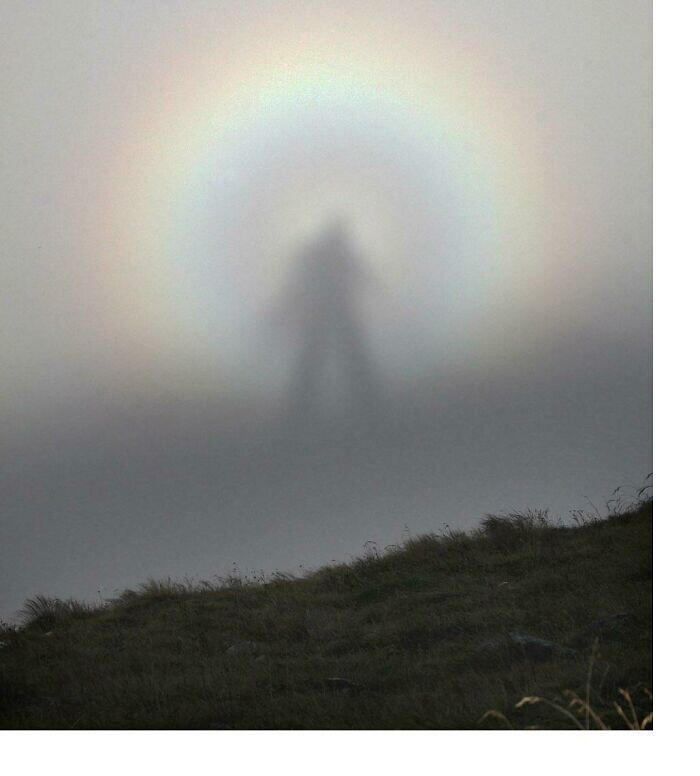 На фото - оптическое явление под названием "брокенский призрак". Это тень наблюдателя на поверхности тумана (или облаков) в направлении, противоположном Солнцу. Чтобы лицезреть его, нужно смотреть вниз со склона горы