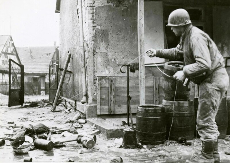 Американский солдат при помощи проволоки или веревки проверяет немецкий гранатомёт на наличие мины-ловушки. 1945 год.