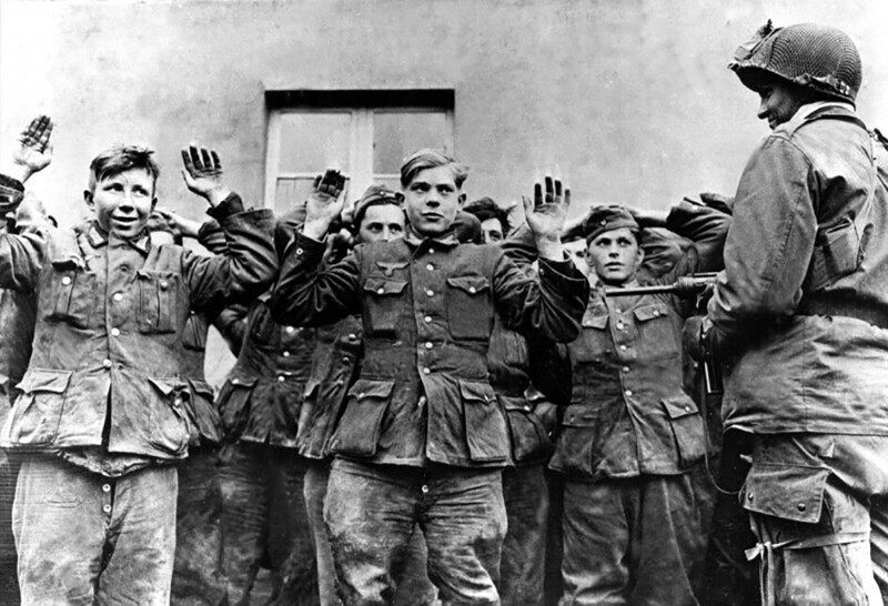 Рядовой Герберт Норман из 17-й воздушно-десантной дивизии США охраняет молодых солдат Вермахта, взятых в плен. Мюнстер, Германия, 1945 год
