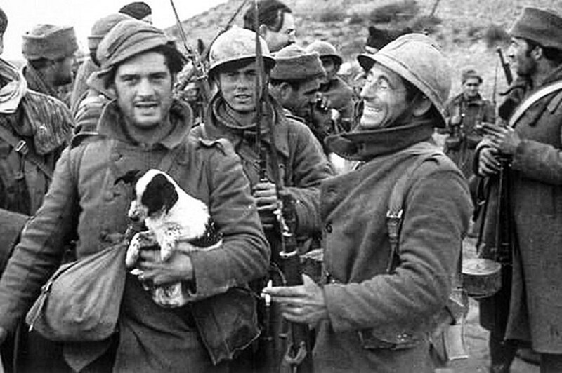 Джордж Оруэлл держит щенка вместе с сослуживцами во время Гражданской войны в Испании, 1937 год. На заднем плане виден Эрнест Хемингуэй