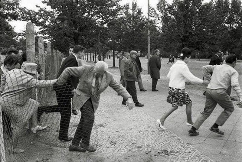 Жители Восточного Берлина бегут на Запад через дырку в заборе, пока пограничники не видят, Берлин, 15 августа 1961 года.