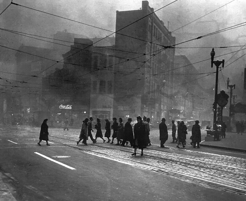 Люди идут по центру Питтсбурга на углу улиц Свободы и Пятой авеню. Загрязненный воздух из-за постоянного использования угля при отоплении и сжигании мусора в городе значительно затемняет это фото, сделанное примерно в 10.35 утра. 1938 года