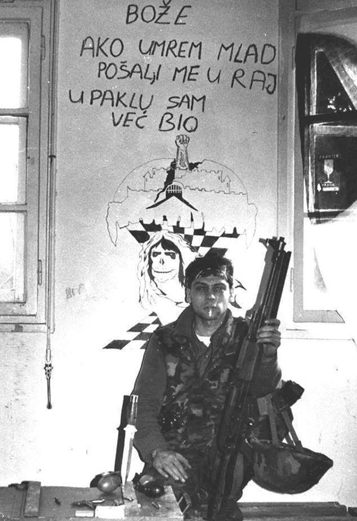 12. Хорватский солдат перед стеной, на которой написано: "Боже, если я умру молодым, пошли меня на небеса; в аду я уже был"