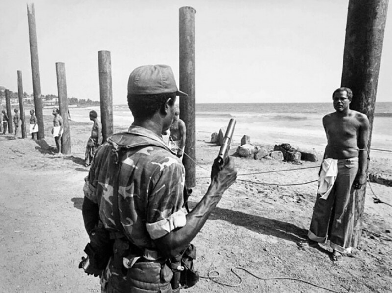 Солдат либерийской армии готовится казнить бывшего члена кабинета министров после государственного переворота 1980 года. Министр на фотографии: Сесил Деннис