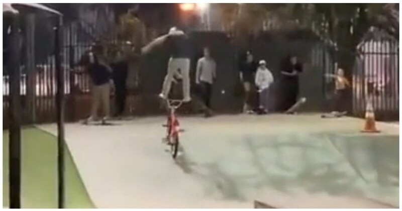 Экстремал катается по скейт-парку, стоя на руле велосипеда