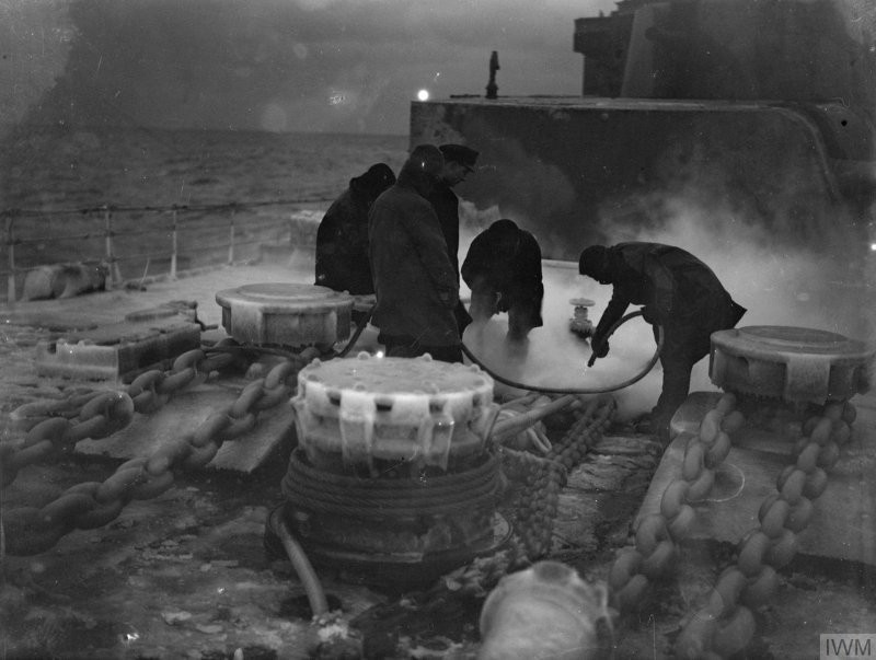 Кочегары лёгкого крейсера Шеффилд за процедурой "откачивания" паром промерзших цепей и концов, заведённых на швартовный шпиль на баке, 1941-й г.