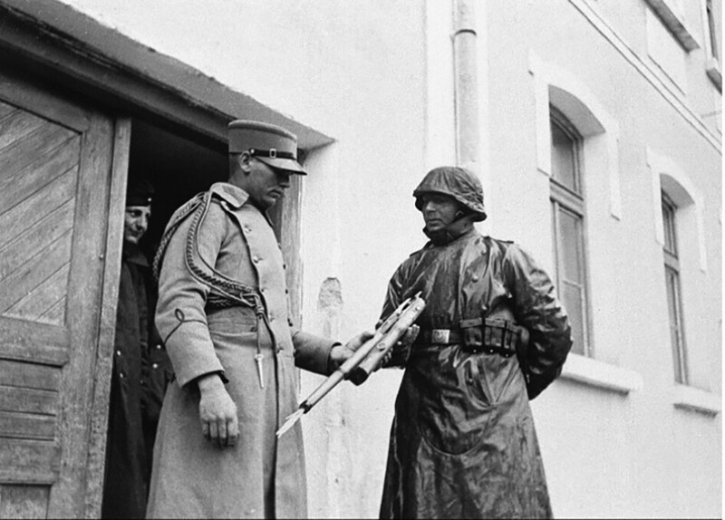 Югославский офицер сдает сломанную винтовку немцу на выходе из казармы. 1941 год