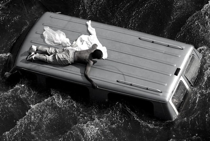 9. Мужчина карабкается на крышу автомобиля на затопленных улицах Нового Орлена. Ураган Катрина, 4 сентября, 2005 года