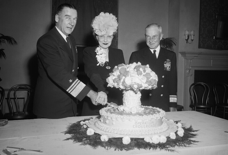 Вице-адмирал Уильям Х. П. Блэнди, его супруга, и контр-адмирал Франк Дж. Лоури перед праздничным тортом по случаю успешных ядерных испытаний в рамках операции «Перекресток» которые проводились США на атолле Бикини. 5 ноября 1946 года