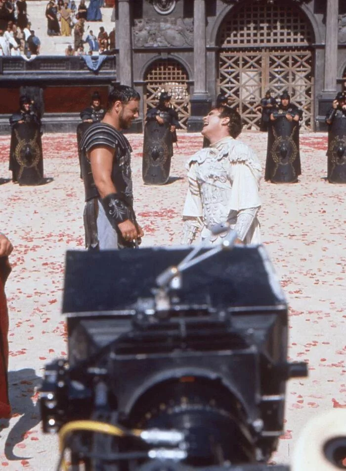 Рассел Кроу с сигаретой в руке и Хоакин Феникс шутят во время съемок финальной дуэли в фильме «Гладиатор» (1999)
