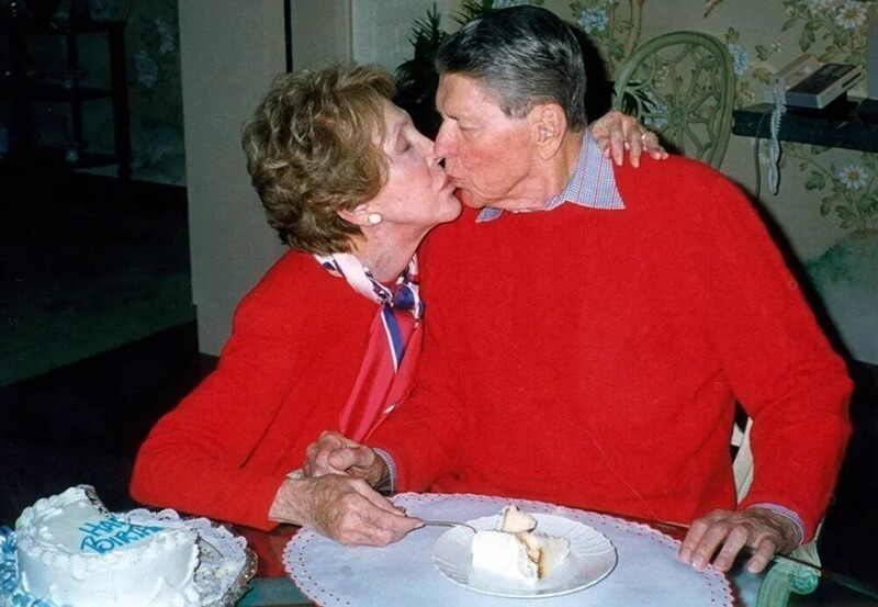 Рональд Рейган целуется со своей женой Нэнси Рейган во время празднования своего 89-летия