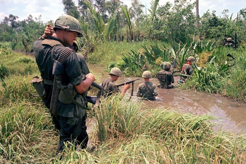 Американские солдаты пробираются через болото в ходе войсковой операции на юге Вьетнама в дельте реки Меконг, апрель 1967 года