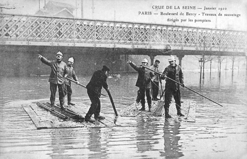 Пожарные плывут на вызов во время наводнения в Париже, январь 1910 года
