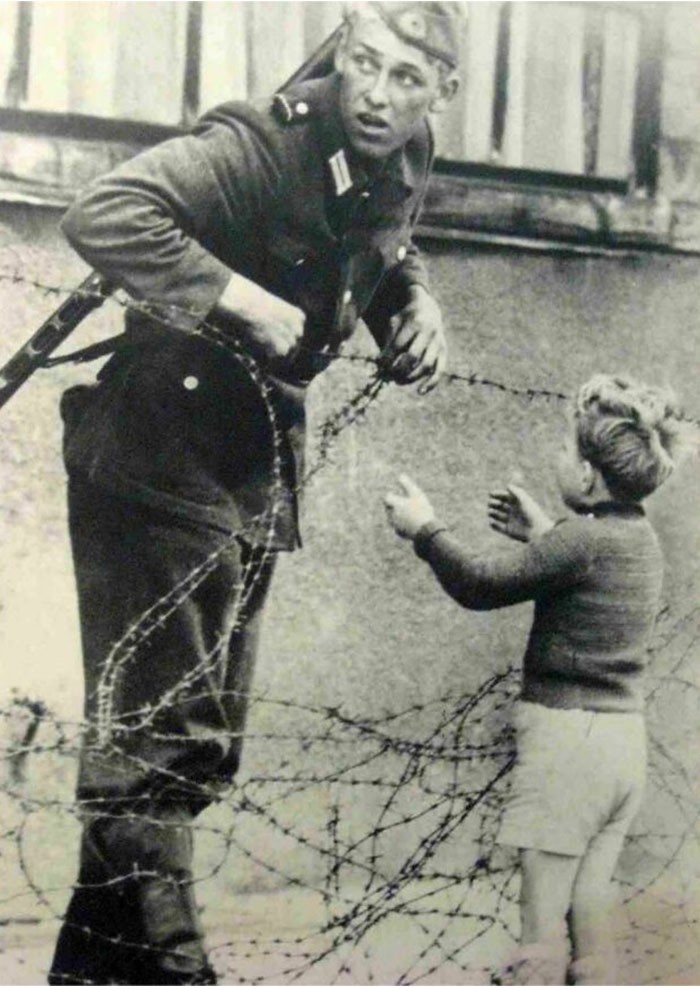2. 1961 год. Солдат из Восточной Германии игнорирует приказ, помогая мальчику пересечь Берлинскую стену, чтобы тот воссоединился со своей семьей