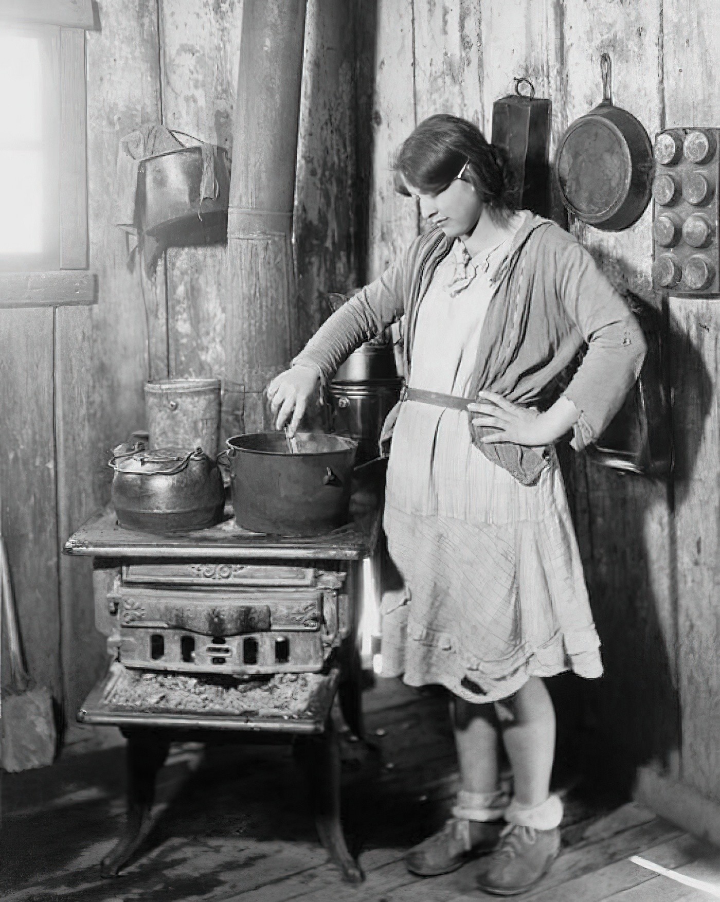 28. Дочь обедневшего фермера из Арканзаса готовит еду на старой плите, пока ее мать в туберкулезном санатории во время Великой депрессии. Фото Красного Креста, примерно 1930 г.