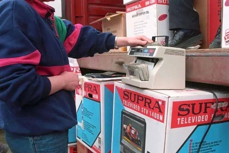Продавец пересчитывает деньги перед продажей видеодвойки на рынке, 1990-е