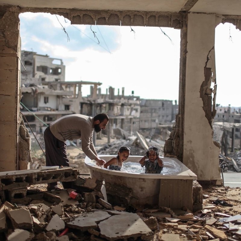 Отец купает свою дочь и племянницу в разрушенном доме в Газе. 2015