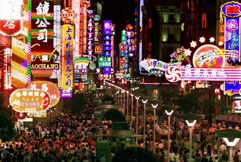 12. Покупатели толпятся под яркими неоновыми огнями на оживленной Нанкин-роуд в Шанхае