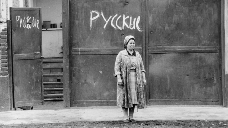 Женщина перед воротами своего дома с надписью «Русские», 1990 год, Баку