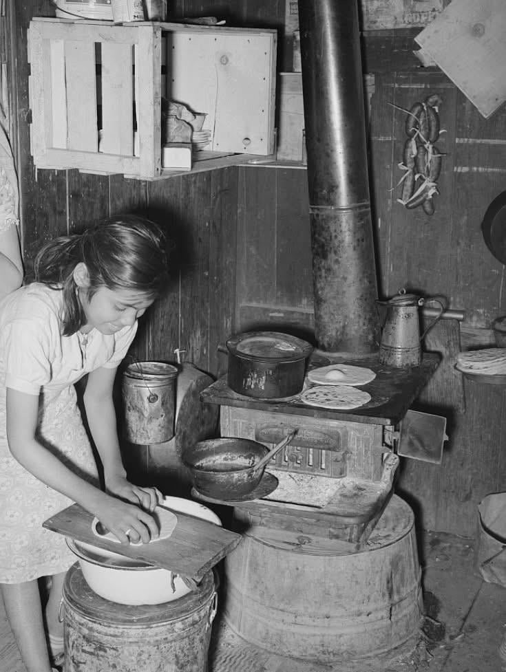 12. Счастливая мексиканская девочка делает тортильи и жарит их на дровяной плите в Робстауне, Техас, 1939 год
