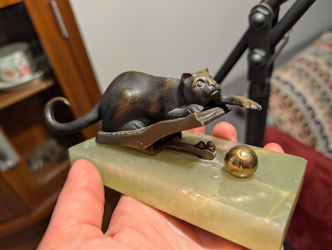 5. Металлическая фигурка кота на обложке книги, охотящегося за мячом