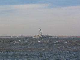 Я не буду спорить. Я лучше покажу фотографии статуи.
Первая фотография показывает насколько далеко Статуя от Манхеттена с которого плавают паромы и прогулочные катера. Там (на Манхеттене) конечно есть метро, но оно находится глубоко под землей.
Вторая фотография показывает как далеко находится берег с ракурса, который на твоем рисунке (а статуя смотрит на Бруклин).
А вопросы твои почему-то мне напомнили информацию, которую печатают в рекламных буклетах для туристов. Тем более, что с аэропорта намного удобней доехать до точки назначения на тахи/кар-сервисе. Поездка на общественном транспорте займет кучу времени и нервов.
Но если кому-то и прийдет в голову с аэропорта поехать сразу на небережную не заезжая в гостиницу или место, где человек будет ночевать, то наиболее быстрый способ на общественном транспорте будет (из JFK): Сесть на Air Train ($5), потом сесть на линию А (еще $2.75), а потом на станции Jay St Мetro Tech пересесть на линию R и доехать до Whitehall St South Ferry. Есть вариант дешевле: из аэропорта сесть на автобус, например на Q10, доехать до Ozone Park, пересесть там на линию А, ну а дальше как в варинте 1. стоимость такого проезда будет $2.75. Но, повторяю так извращаться мало кто захочет, проще и удобней на доехать на такси. Вторым аэропортом Laguardia я не пользовался, так что про него говорить не буду.