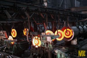 Прям ностальгия.
Я проходил практику в 2000 на Выксунском колёсопрокатном цехе.
Практически один в один.
Из выбитых прессом середин заготовок получались не хилые гантели.
А из "чешуи" это на закалочной линии были такие листы 10 мм толщиной получались отличные ножи, топоры, мечи, причём разрубали гвоздь на ура без зазубрин.
На фото видны эти листы. На этих крюках происходит закалка колёс в печи.