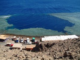 Еще одно интересное местечко
На побережье Красного моря севернее Дахаба находится Голубая дыра (Blue Hole) — одно из лучших мест на Синае и опаснейшее место для дайверов. Голубая дыра представляет собой вертикальную пещеру, уходящую в глубину Красного моря на 100 метров, окруженную коралловыми рифами. Как образовалась эта отвесная пещера, диаметром не менее 50 метров, геологи точно объяснить не могут. Туристы устремляются сюда, чтобы заглянуть в бездну с борта прогулочного катера, а самые смелые погружаются под воду, стремясь увидеть своими глазами, почувствовать завораживающий призыв бездны. Оттолкнувшись от края пещеры, дайвер устремляется в темноту. Другое название этого места — Кладбище дайверов, неслучайно. Маршрут погружения, не отличающийся сложностью, забрал более сотни жизней.
Пэ эс: на видео чемпион мира по фридайвингу Гийом Нери ныряет в Голубую дыру