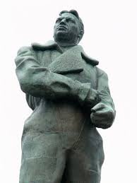 на памятнике показывает всем известный жест. его потом часто цитировал Лебедь