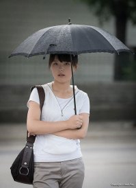 Я бы даже больше сказал : - Девушка с чёрной сумкой , в серых брюках и белой кофточке под чёрным зонтом